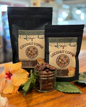 Two packages of Kauai Gourmet Nuts Coconut Coffee on a wooden surface with a flower and jar of coffee beans.