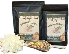 Two packages of Kauai Gourmet Nuts Rosemary Garlic mixed nuts with a small scoop of nuts and a flower on a white background.